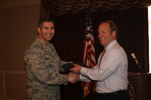 Chapter President Col. Scott Merrell, USAF (l), vice commander, 72nd Air Base Wing, gives Lt. Col. Stan Chase, USA (Ret.), chief operating officer, Perimeter Technology Center, a gift for his presentation at the April luncheon. 